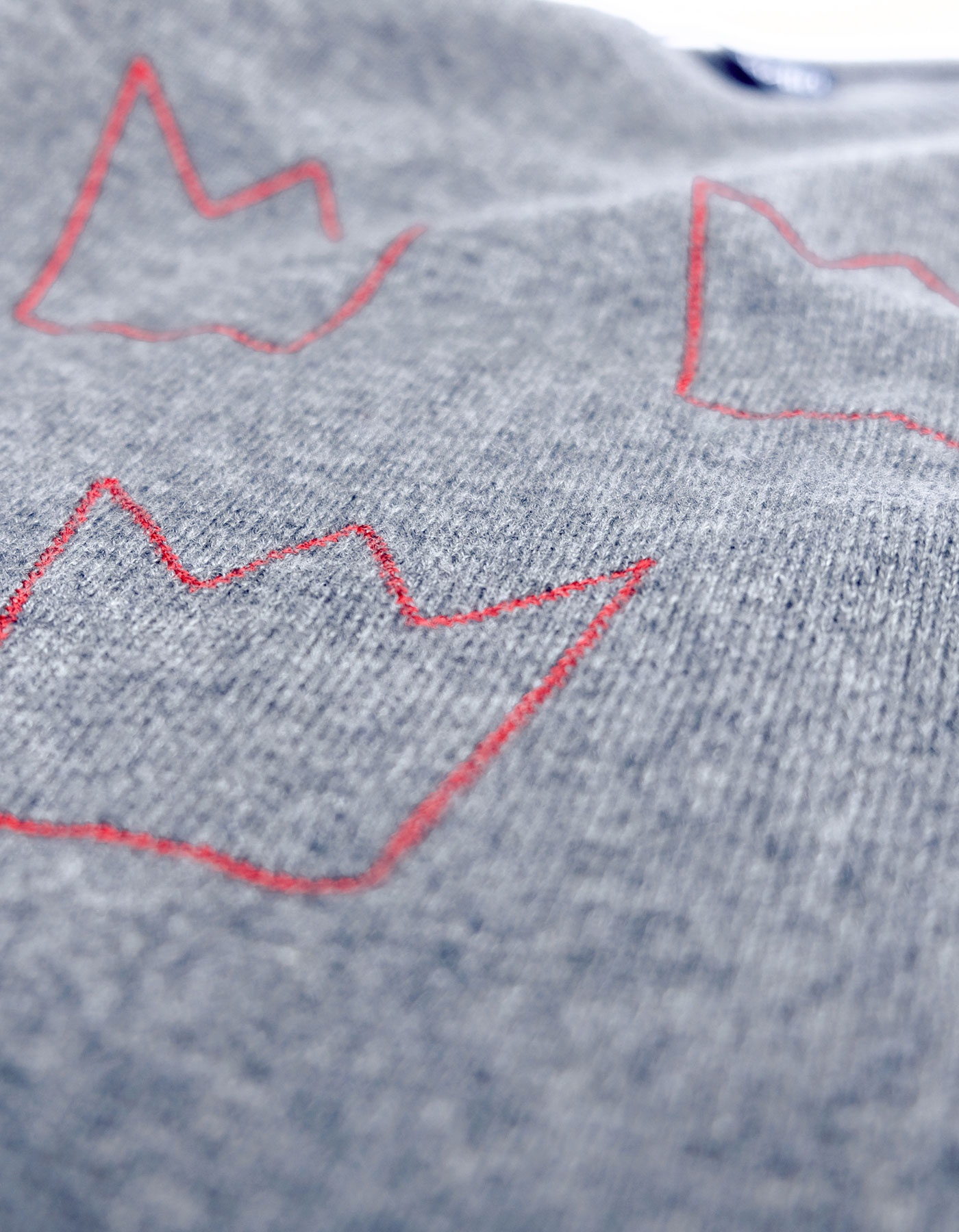 Close up of malin darlin cashmere knitwear showing three crowns knitted into the pattern of the jumper.