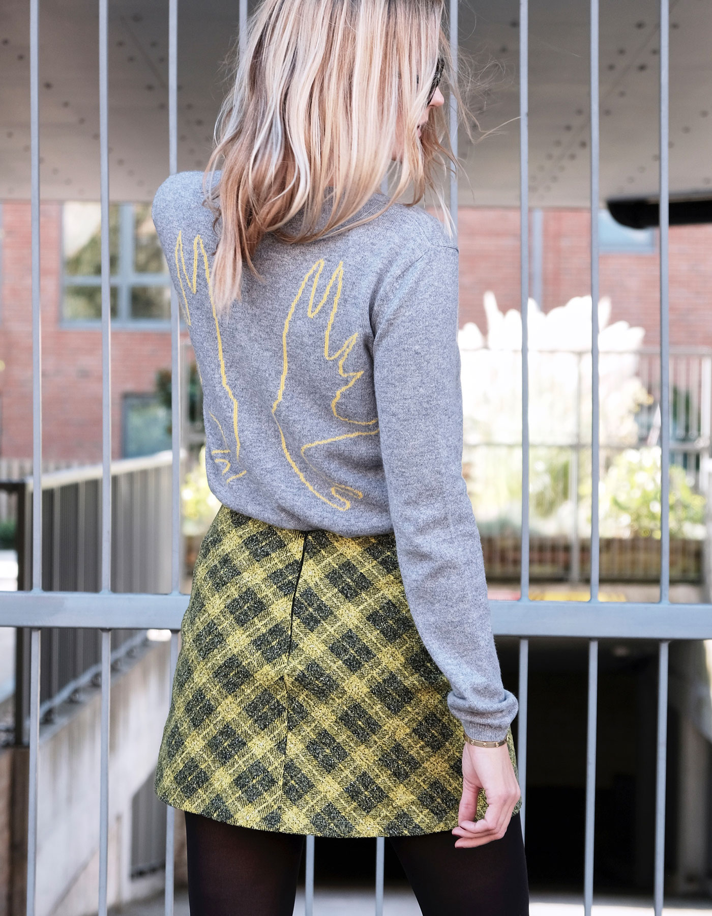 A model wearing a Malin Darlin Antlers cashmere Intarsia jumper, check mini skirt and black opaque tights.