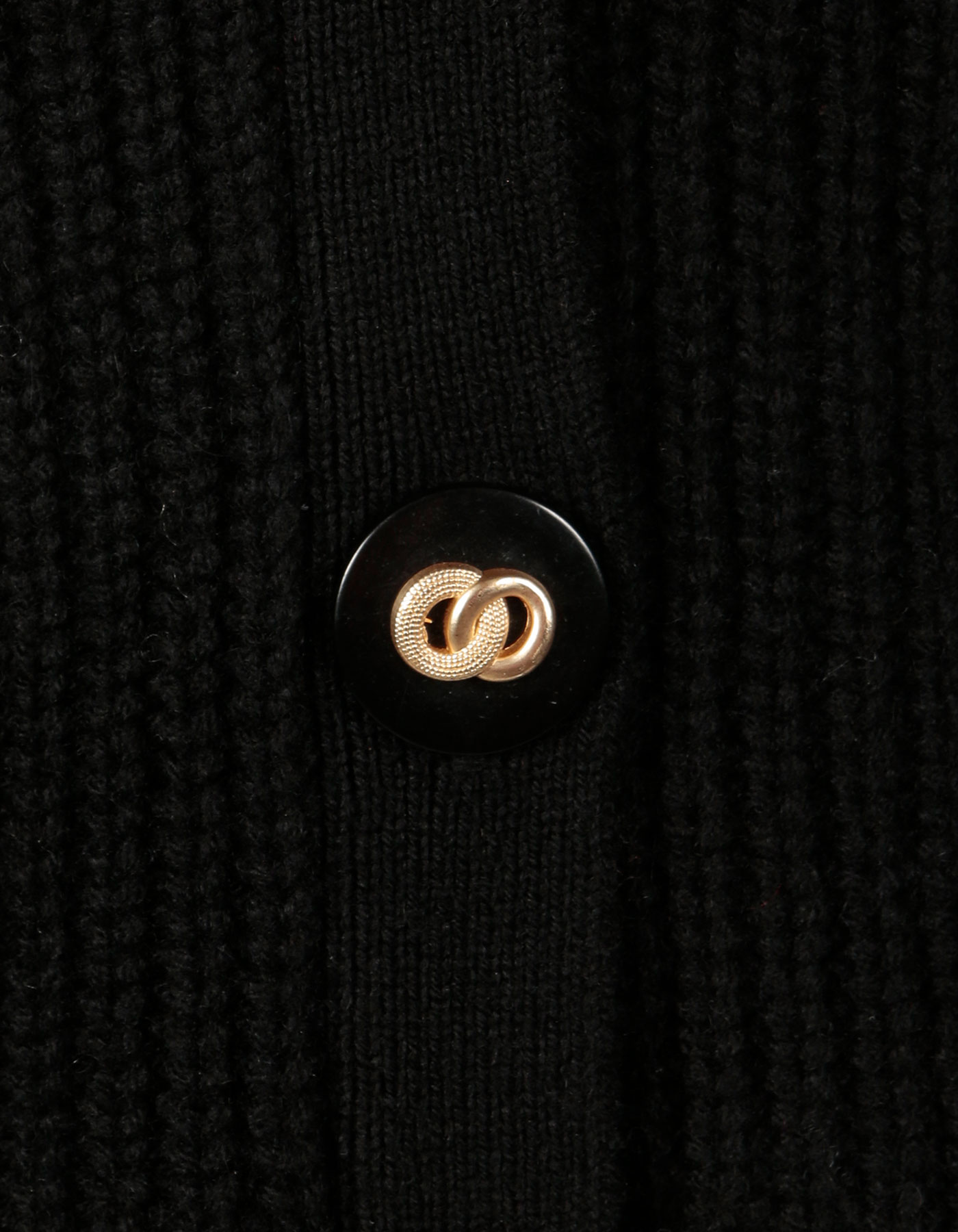 Button detail, two gold rings entwined, on a malin darlin black Coco rib wool and cashmere cardigan.